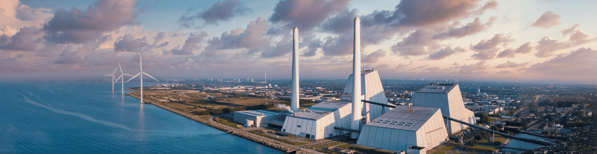 Vista panorâmica de usina de recuperação energética ao lado do mar, com turbinas eólicas
ao fundo, representando soluções sustentáveis para resíduos sólidos.