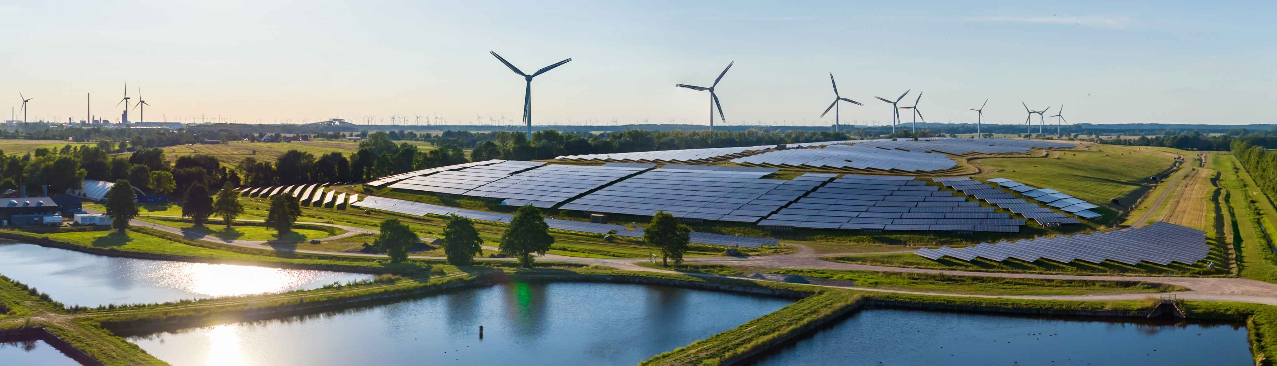 Complexo de energia renovável com placas solares e turbinas eólicas instaladas em área rural, simbolizando a transição energética sustentável.